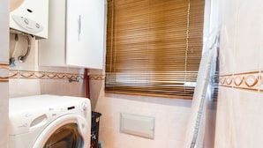A compact bathroom with a washing machine, a toilet, and a shower area. - Sweet Home Reis Magos by Atlantic Holiday (Caniço)