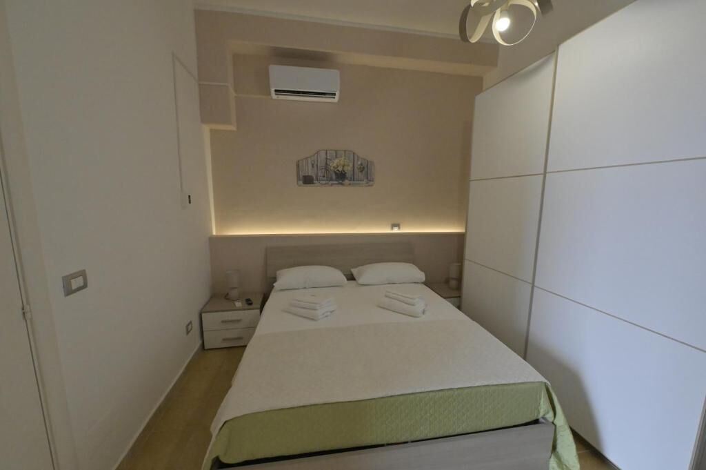 Ein Hotelzimmer mit Bett, Nachttischen, einer Klimaanlage und einem Wandbild.