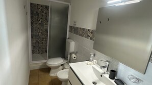 Ein kleines Badezimmer mit Toilette, Bidet und Waschbecken mit Spiegel.