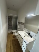 A compact bathroom with a toilet, bidet, and a sink with a mirror.