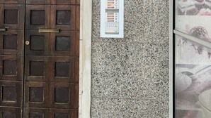 Eine Gebäudefassade mit einer Holztür, einer Granitwand mit einem Schild und einem Brandmelder.