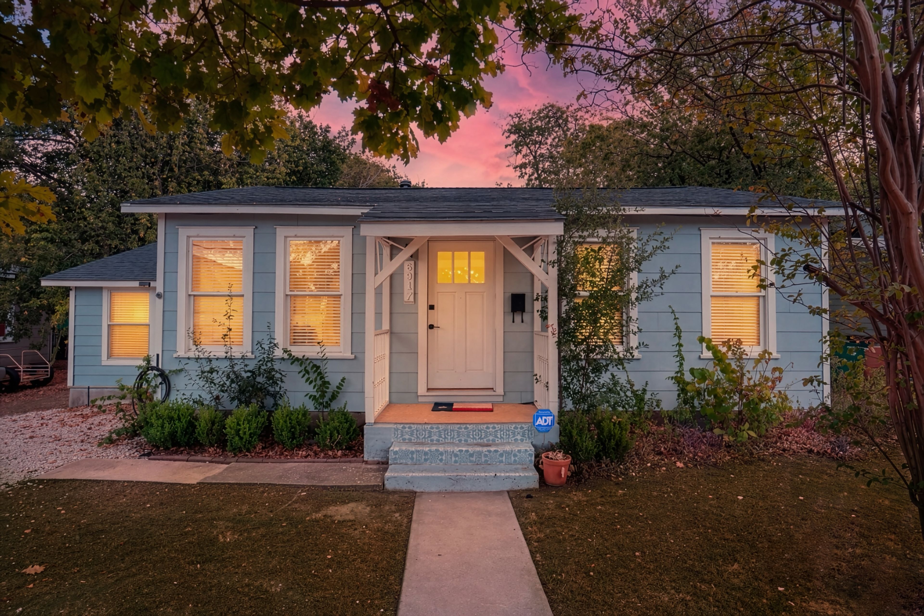 A single-story house with a front porch, a mailbox, and a small garden area.