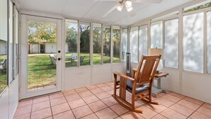 A sunroom with a ceiling fan, a rocking chair, and a view of a backyard. - 3BR in Crestview • 2 Kings • UT • Downtown • Events • Free Parking (Austin)