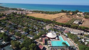 An aerial view of a coastal resort with a swimming pool, beach, and residential buildings. - Happy Camp in Kamemi Camping Village (Ribera)