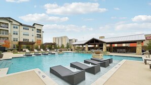 A swimming pool with lounge chairs and a covered area, surrounded by multi-story buildings. - Landing | Beautiful 1BD, Clubhouse, Courtyard (Denton)