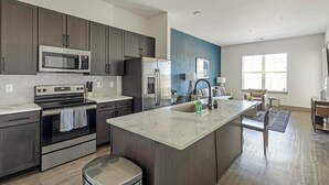 Una cocina moderna con electrodomésticos de acero inoxidable, una isla central y una pared azul de acento.