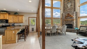 A spacious kitchen with wooden cabinets, a dining area with a stone fireplace, and large windows offering a view of the outdoors.