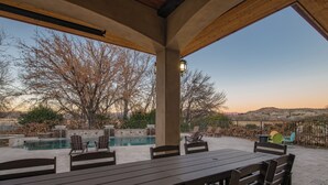 Um pátio externo com piscina, área de estar e vista para a paisagem.