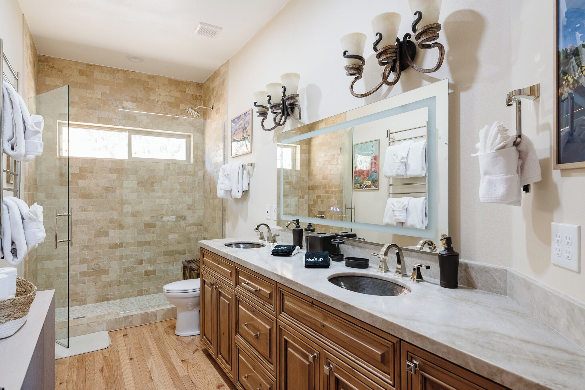 A modern bathroom with a glass shower enclosure, a large mirror, and dual sinks.