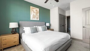 A neatly arranged bedroom with a bed, two bedside tables, and a door leading to a bathroom.
