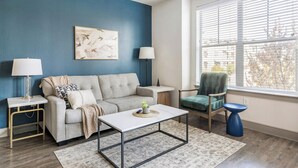 Un salon avec un canapé, une table basse, un fauteuil et une lampe.