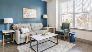 A living room with a sofa, a coffee table, a chair, and a lamp.