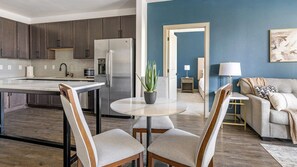 A modern kitchen with dark cabinets, a stainless steel refrigerator, and a white island with a plant.