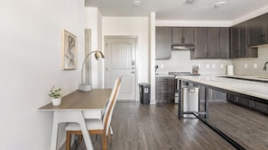 A modern kitchen with a central island, dark cabinets, and a white countertop.