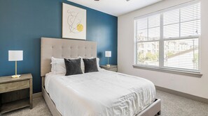A bedroom with a large bed, two bedside tables, a window with blinds, and a wall-mounted artwork. - Landing | Amazing 2BD, Courtyard, Clubhouse (Denton)