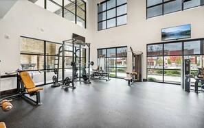 A spacious gym with various exercise equipment, large windows, and a view of the outdoors. - Landing | Modern 2BD, Clubhouse, Gym (Denton)
