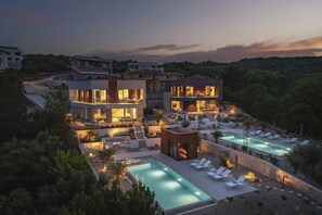 Una villa moderna con piscina, mobiliario exterior y una terraza bien iluminada.