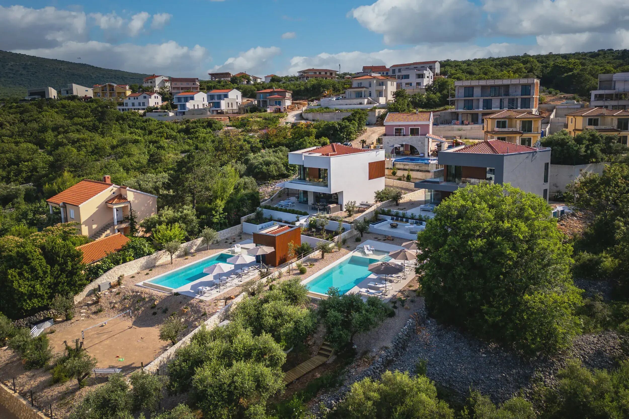 A residential area with modern houses, a swimming pool, and a tennis court.