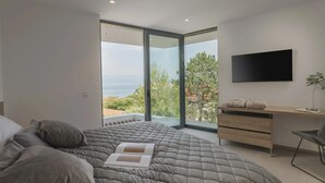Ein modernes Schlafzimmer mit einem großen Bett, einem Schreibtisch und einem Fernseher.