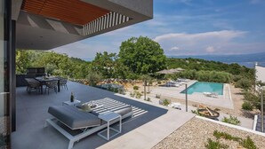 A modern outdoor patio with a dining area, lounge seating, and a swimming pool. - Villa Moana on Krk - Crovillas (Vrbnik)