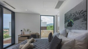 A modern bedroom with a large bed, a desk, and a view of the cityscape. - Villa Moana on Krk - Crovillas (Vrbnik)