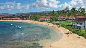 A beach resort with clear turquoise waters, palm trees, and a sandy beach.