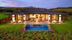A modern house with a swimming pool, outdoor seating, and a view of the mountains.