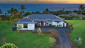 A house with a large front yard, a driveway, and a view of the ocean.