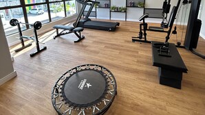 A modern gym with a trampoline, treadmills, and weight machines. - Melhores Flats - Elegante perto da praia (João Pessoa)
