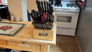 A kitchen with a wooden cutting board holding steak knives, a white stove, and a red pepper on a cutting board.