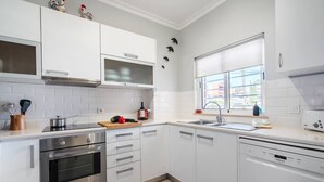 A modern kitchen with white cabinets, stainless steel appliances, and a dishwasher. - Bright and modern 2 Bed Apartment in Vale de Parra (Guia)