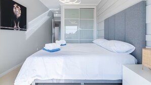 A modern hotel room with a large bed, a grey headboard, and a city view through a sliding door. - Bright and modern 2 Bed Apartment in Vale de Parra (Guia)