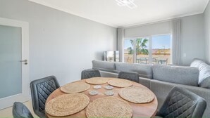 A modern living room with a round wooden table, grey sofas, and a balcony with a view. - Bright and modern 2 Bed Apartment in Vale de Parra (Guia)