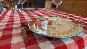 A dining table with a red and white checkered tablecloth, a floral plate, a wine glass, and cutlery.