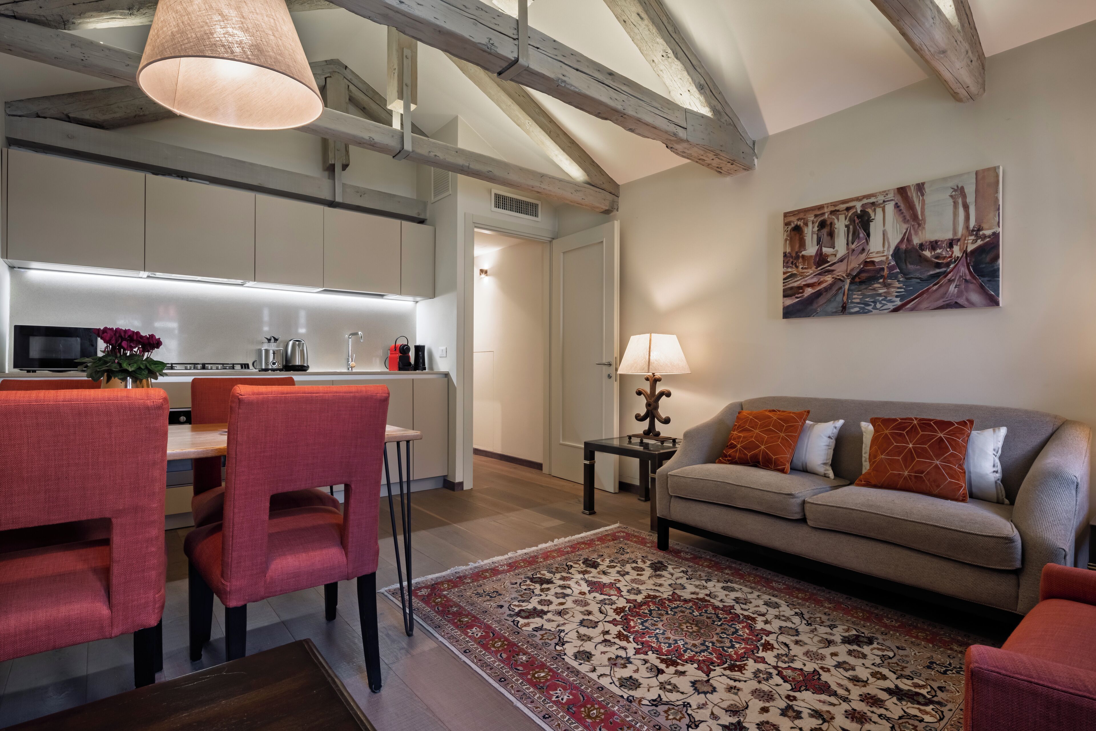 Un salon moderne avec un canapé, des fauteuils, un tapis et un tableau accroché au mur.