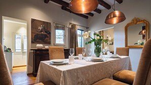 A dining room with a table set for four, featuring a white tablecloth and floral centerpiece.