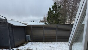 A wooden deck with a potted plant, a shed, and a fence. - Family house in Mosfellsbær (Mosfellsbær)