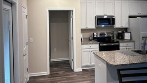 A modern kitchen with white cabinets, a granite countertop, a stainless steel microwave, and a black stove. - Charming 3-bedroom 2-bath new build in the heart of crestview (Crestview)