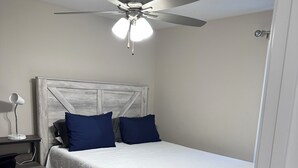 A bedroom with a bed, a desk, a chair, a ceiling fan, and a nightstand. - Charming 3-bedroom 2-bath new build in the heart of crestview (Crestview)