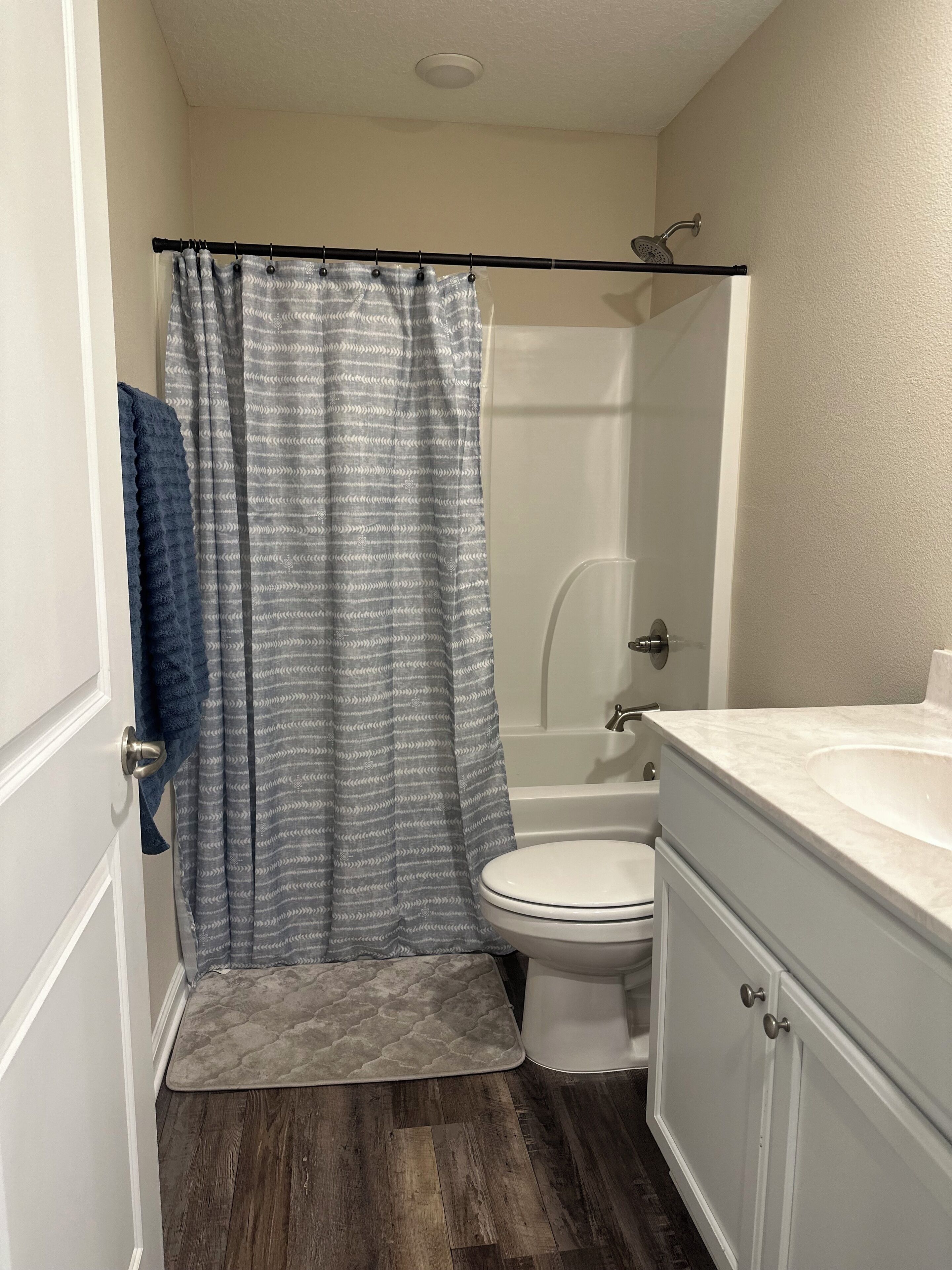Une salle de bain avec un rideau de douche, des toilettes et un lavabo.