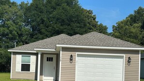 A single-story house with a garage, a front door, and a small porch. - Charming 3-bedroom 2-bath new build in the heart of crestview (Crestview)