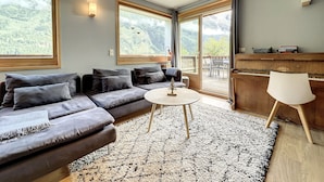 Een moderne woonkamer met een grijze modulaire bank, een klein rond tafeltje en een piano.