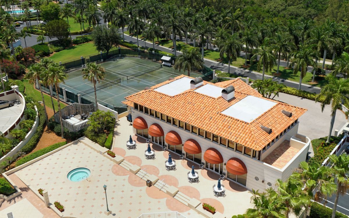 Un hôtel doté d’une cour intérieure comprenant un court de tennis, un espace salon extérieur et une piscine.