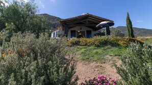 Ein rustikales Haus mit Holzschindeldeckung, umgeben von einem Garten mit verschiedenen Blumen und Sträuchern.