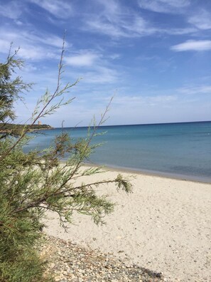 A beach with clear water and a distant island.