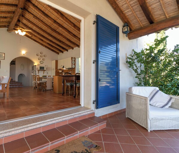 A spacious living area with a kitchen, a dining area, and a seating area with a wicker sofa.