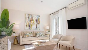 Una sala de estar moderna con sofá, sillón, mesa de centro y televisor de pantalla plana montado en la pared.