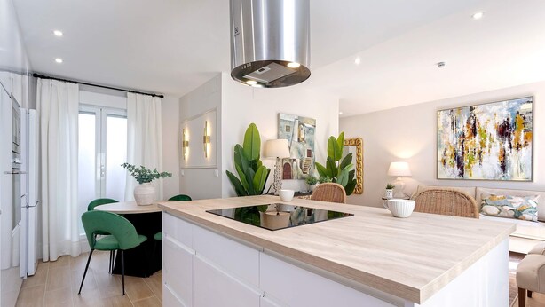 Una cocina moderna con una isla central, armarios blancos y una campana de acero inoxidable.