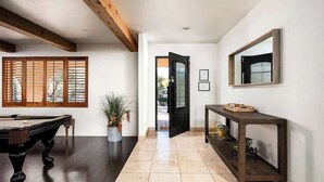Um corredor com mesa de bilhar, console e espelho na parede.