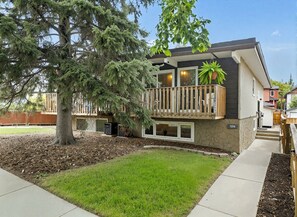 A modern two-story house with a balcony, a large tree in the front yard, and a well-maintained lawn. - Cozy and comfy two-unit home in the Calgary core (Calgary)